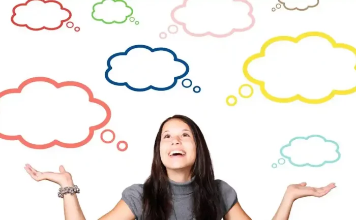 A woman with long dark hair looks upward with a smile, surrounded by colorful thought bubbles of various shapes and sizes on a white background.