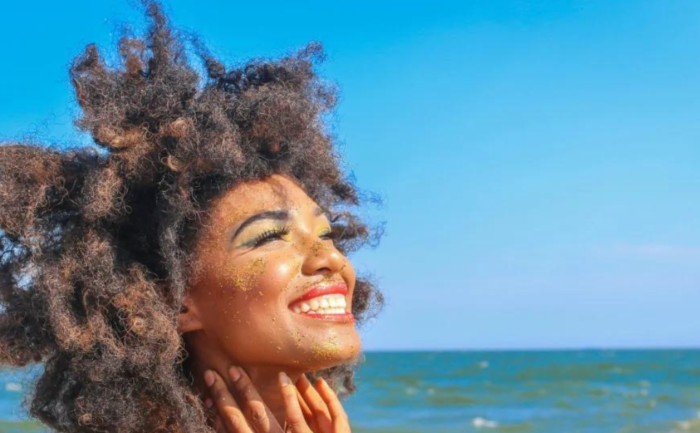 Joyful woman with glitter on her face smiling at the beach